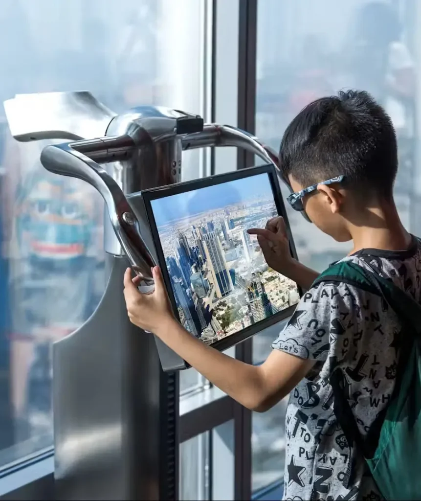 a teen ager seeing dubais skyline through telescope at the top burj khalifa level 124